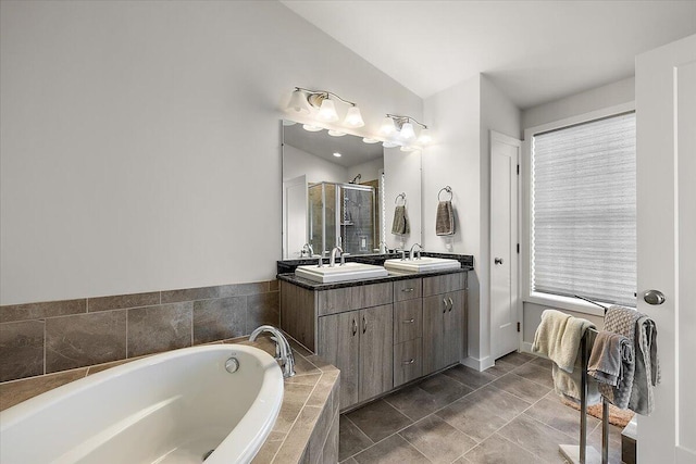 full bathroom with double vanity, a bath, a shower stall, vaulted ceiling, and a sink