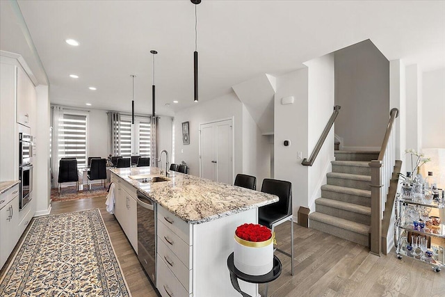kitchen featuring light wood-type flooring, a sink, a breakfast bar area, and a kitchen island with sink