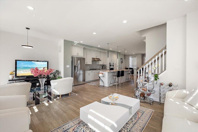 living area featuring recessed lighting, wood finished floors, and stairway