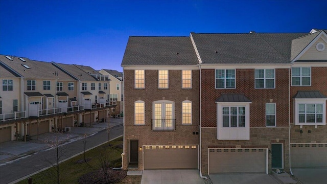 view of property with an attached garage, driveway, and brick siding