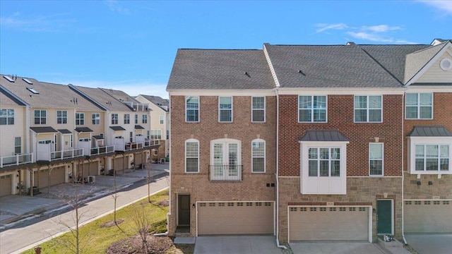 multi unit property with an attached garage, brick siding, driveway, and a residential view