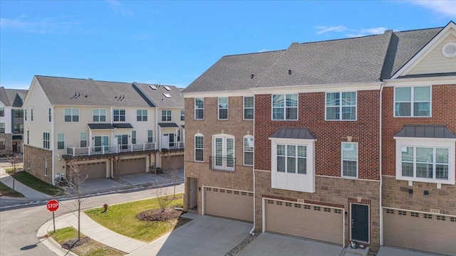 multi unit property featuring a garage, a residential view, driveway, and stone siding