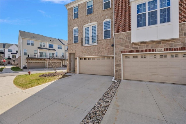 view of property featuring an attached garage, brick siding, driveway, and a residential view