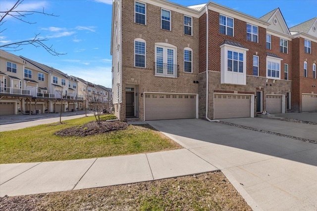 townhome / multi-family property with driveway, a residential view, brick siding, a front lawn, and an attached garage