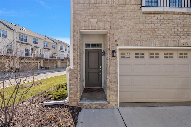 doorway to property featuring a residential view, brick siding, and a garage