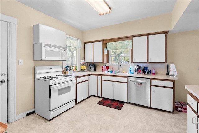 kitchen with white appliances, light floors, light countertops, white cabinets, and a sink