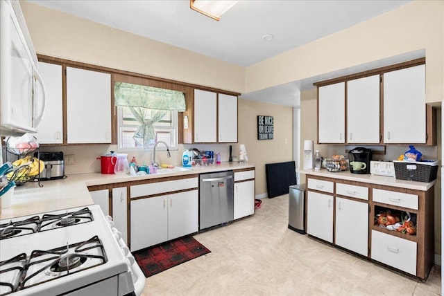 kitchen featuring white appliances, white cabinetry, a sink, and light countertops