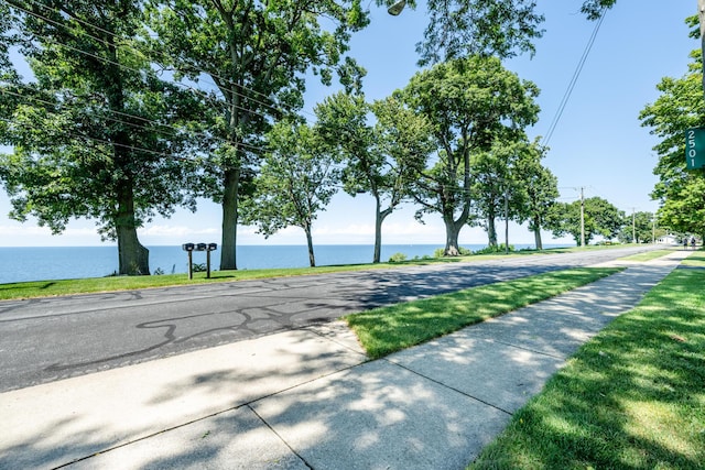 view of road with a water view, traffic signs, and sidewalks