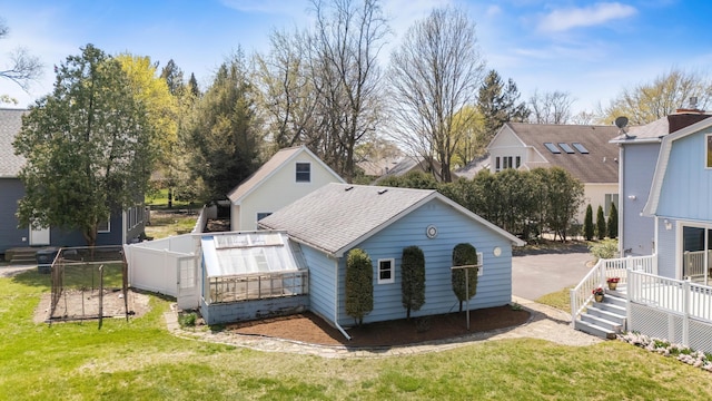rear view of property featuring roof with shingles, a wooden deck, and a yard