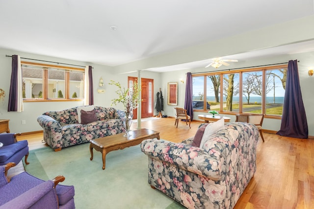 living area featuring baseboards, ceiling fan, and wood finished floors