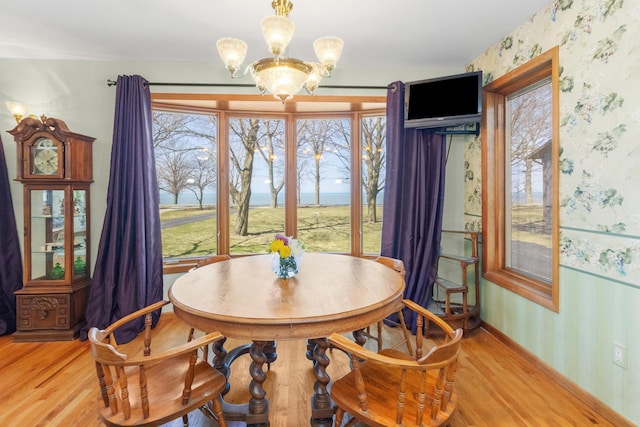 dining space with baseboards, wallpapered walls, a notable chandelier, and wood finished floors