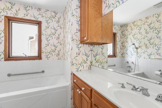bathroom with visible vents, vanity, a bath, and wallpapered walls