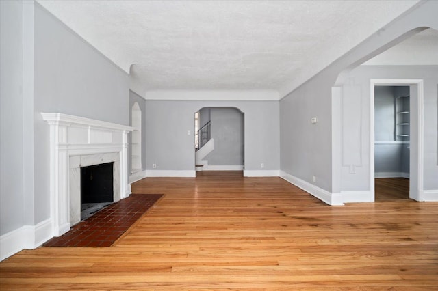 13936 Longacre St, Detroit, MI 48227 - unfurnished living room featuring arched walkways, baseboards, light wood-style flooring, and a fireplace