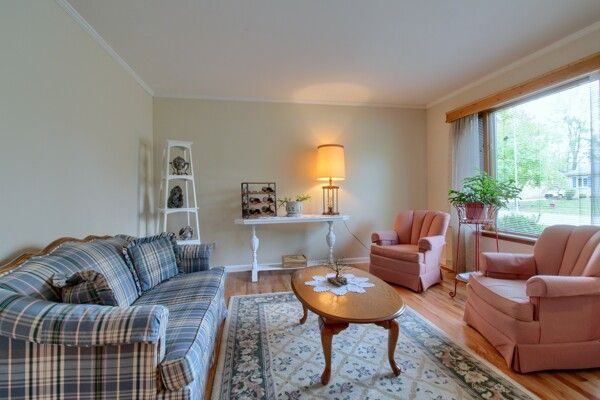 living room featuring baseboards, ornamental molding, and wood finished floors