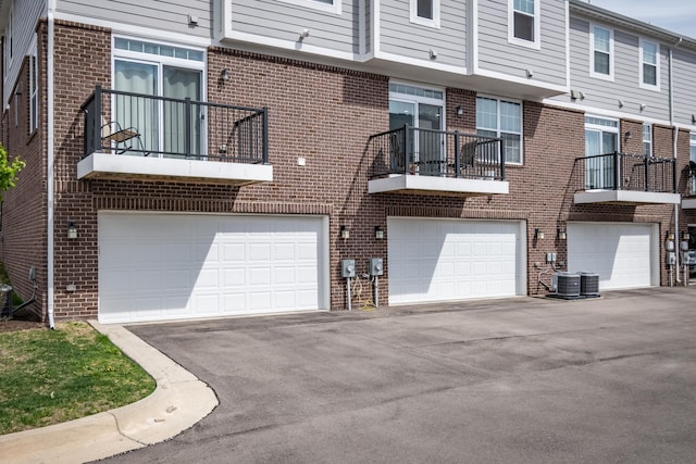 exterior space featuring an attached garage, cooling unit, and driveway
