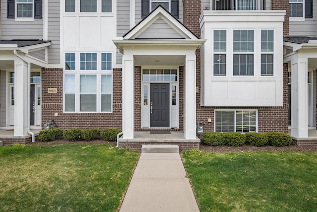doorway to property featuring a lawn and brick siding