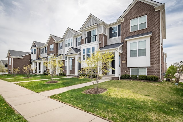 townhome / multi-family property featuring a residential view, a front yard, and brick siding