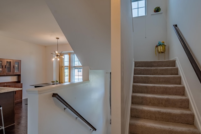 staircase with a notable chandelier, wood finished floors, and a wealth of natural light