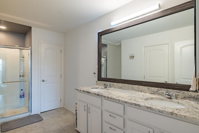 full bathroom featuring double vanity, a sink, baseboards, and a stall shower