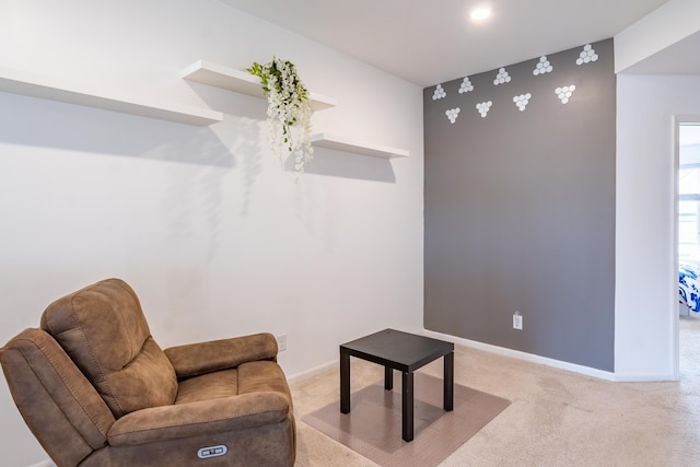 living area featuring baseboards and light carpet