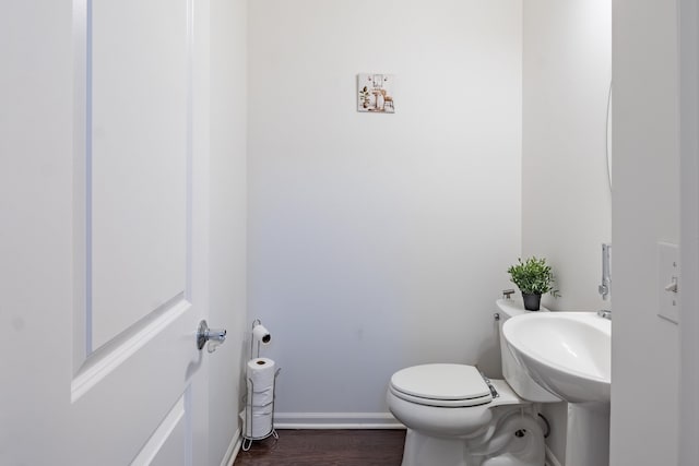 bathroom featuring baseboards, wood finished floors, and toilet