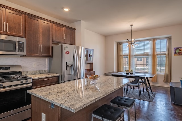kitchen featuring a center island, dark wood finished floors, light stone counters, and stainless steel appliances