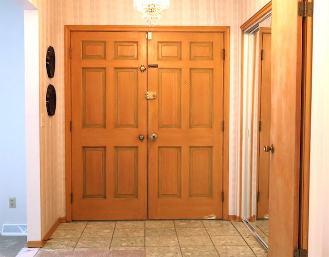 interior space with baseboards, wallpapered walls, a chandelier, and visible vents