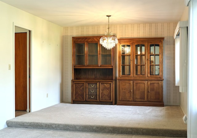 carpeted dining area with wallpapered walls and a chandelier