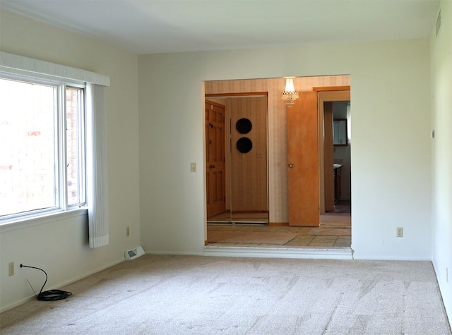 spare room featuring carpet floors, visible vents, and a healthy amount of sunlight