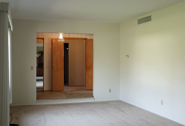 empty room featuring carpet floors, visible vents, and an inviting chandelier