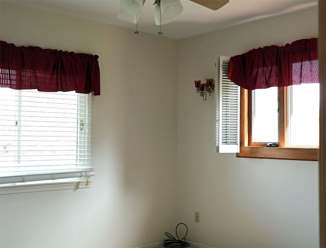 unfurnished room featuring baseboards, ceiling fan, and a wealth of natural light