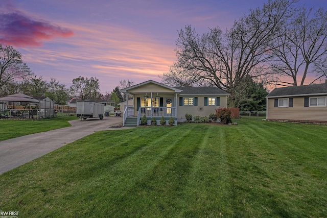 bungalow-style house with fence, covered porch, driveway, and a front lawn
