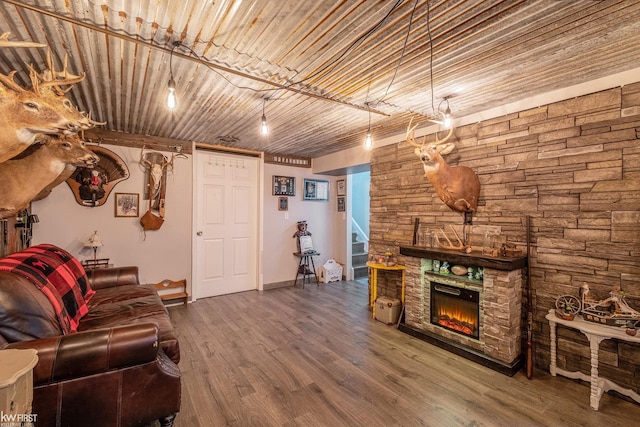 living room with a stone fireplace, baseboards, and wood finished floors