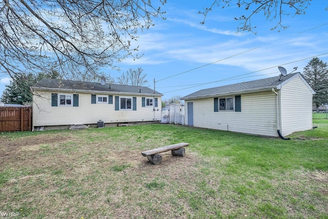 rear view of house with fence and a lawn