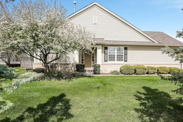 view of front of property with brick siding, a shingled roof, and a front yard