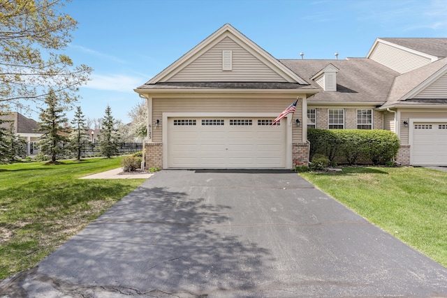 multi unit property featuring an attached garage, a front yard, aphalt driveway, and brick siding