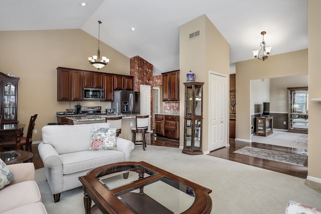 living room with high vaulted ceiling, a notable chandelier, baseboards, and carpet