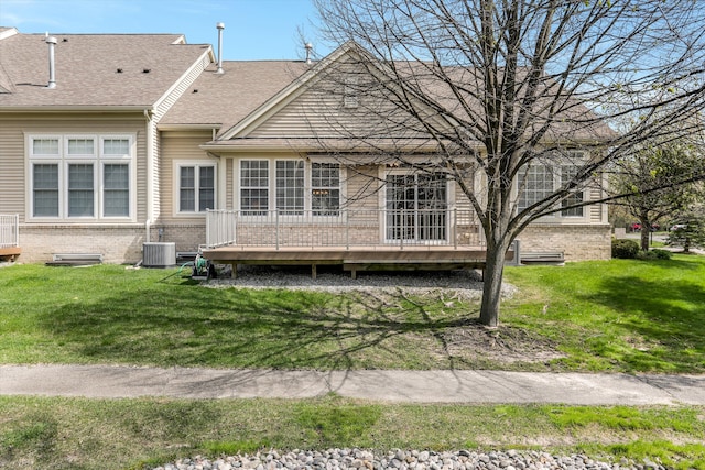 back of property featuring roof with shingles, a yard, a deck, and brick siding