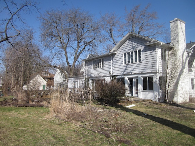 back of house featuring a chimney and a yard