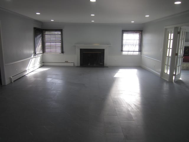 unfurnished living room featuring a fireplace with flush hearth, wainscoting, recessed lighting, and a baseboard heating unit