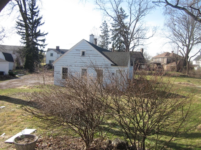 view of side of home with a chimney and a shingled roof