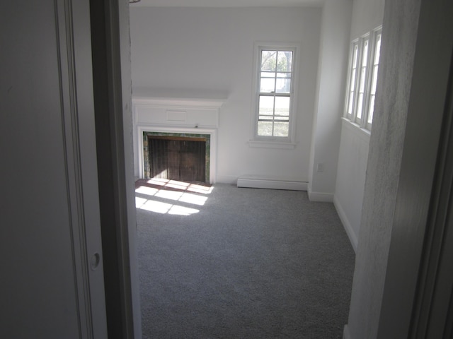 unfurnished living room featuring baseboards, carpet flooring, baseboard heating, and a tile fireplace
