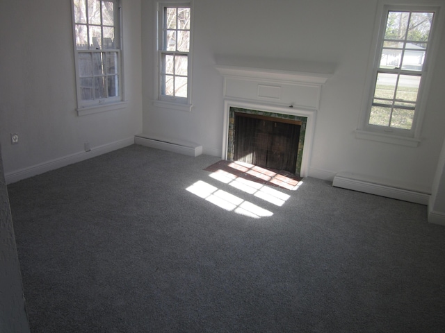 unfurnished living room featuring a tiled fireplace, a baseboard radiator, and carpet