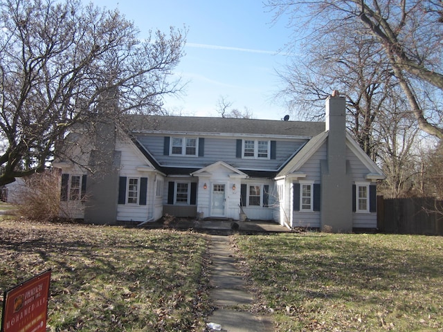 view of front of home featuring fence, a chimney, and a front lawn