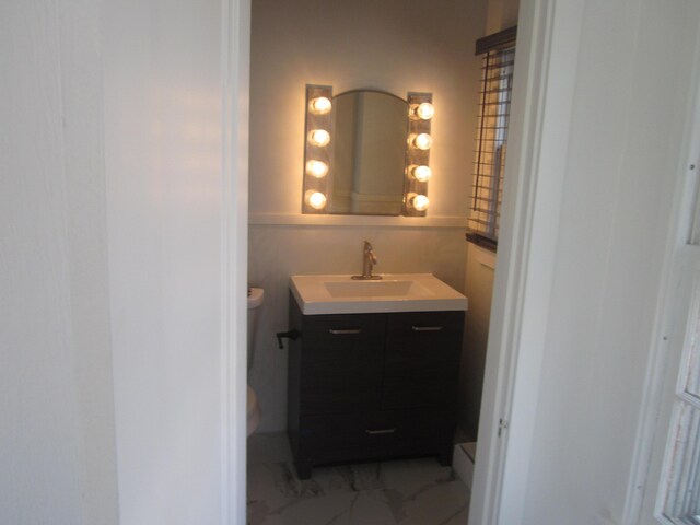 bathroom with vanity, toilet, and marble finish floor