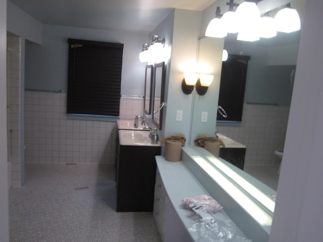 bathroom featuring tile walls, tile patterned flooring, a wainscoted wall, and vanity