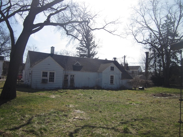 view of side of home with a lawn, french doors, and a chimney