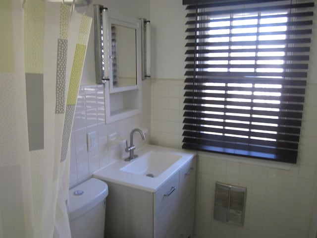 bathroom with visible vents, vanity, toilet, and tile walls