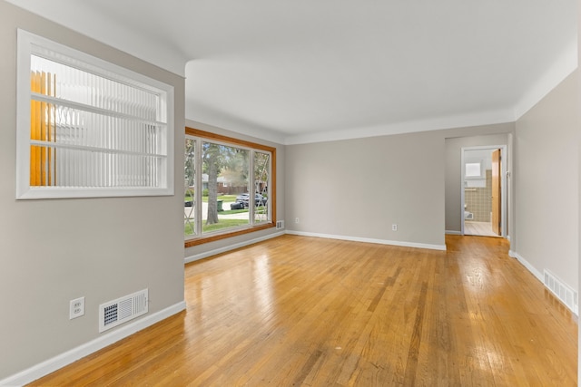 unfurnished living room with baseboards, light wood finished floors, and visible vents