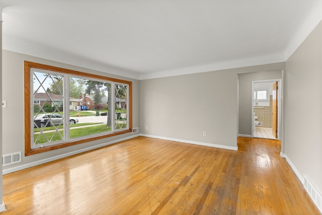 unfurnished room featuring visible vents, light wood finished floors, and baseboards